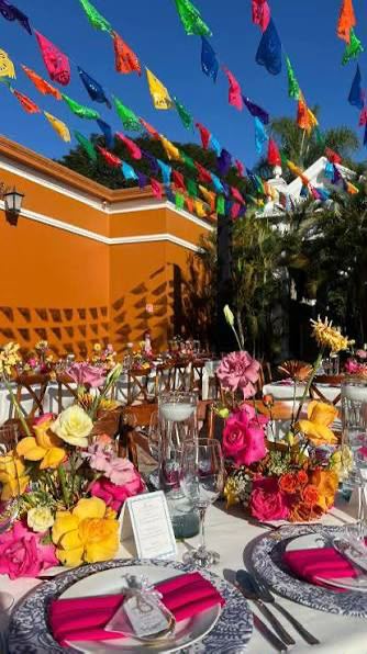 Mesa festiva con papel picado y flores en tonos vivos